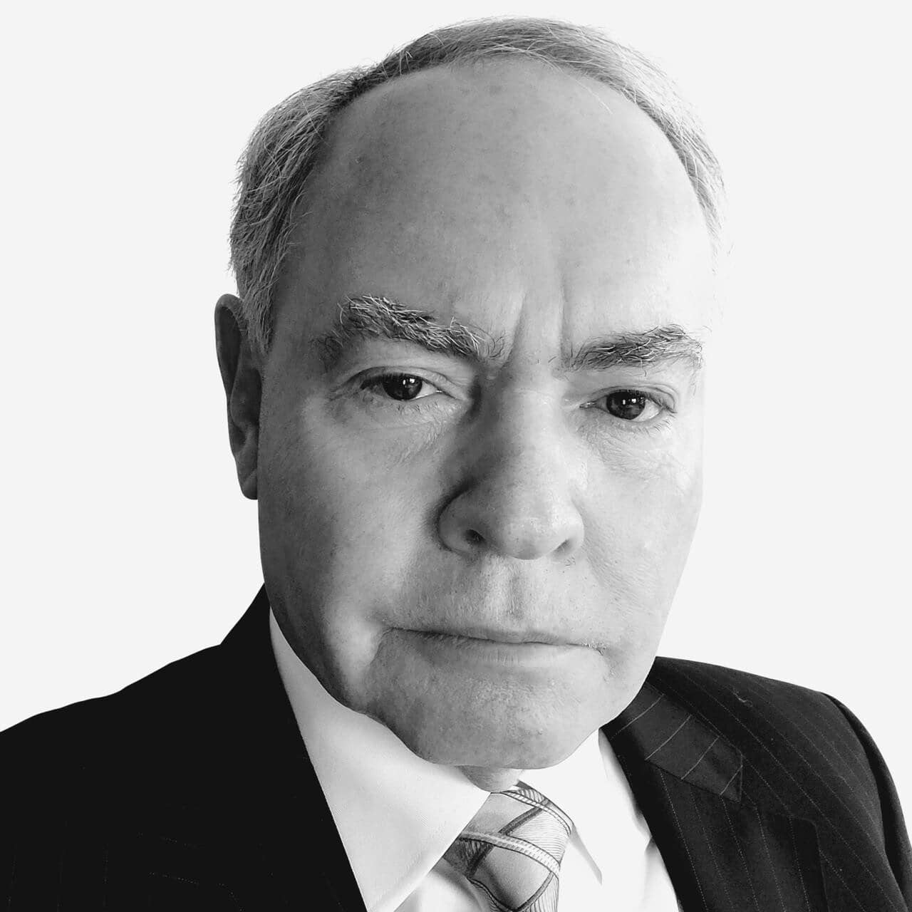Black and white portrait of an older man in a suit and tie, with a neutral expression, facing the camera.