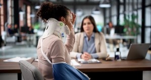 injured woman wearing neck brace and arm sling meeting with legal professional