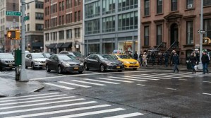 busy urban intersection with taxi, sedans, pedestrians, and stop signal