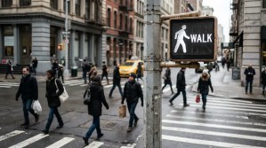 WALK signal sign displayed as pedestrians cross busy urban intersection